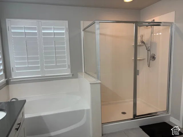 Built-in bathtub, glass-enclosed shower with integrated shelving, plantation shutters, and a vanity with a dark countertop