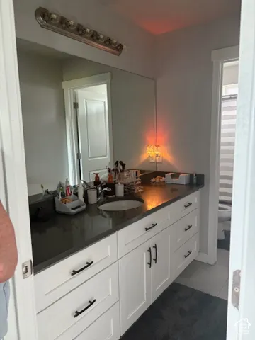 Vanity with white cabinetry, dark countertop, and integrated sink