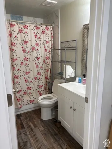 Wood-finish flooring, white vanity with integrated sink, and a built-in tub with tile surround