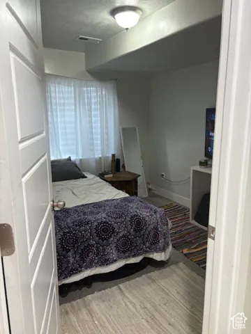White panel door, recessed ceiling section, flush mount lighting, wood-finish flooring, and a window with blinds