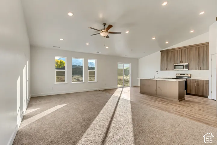 Open-concept living space featuring recessed ceiling lighting, a brushed-metal ceiling fan, and abundant natural light from multi-pane windows and glass sliding doors
