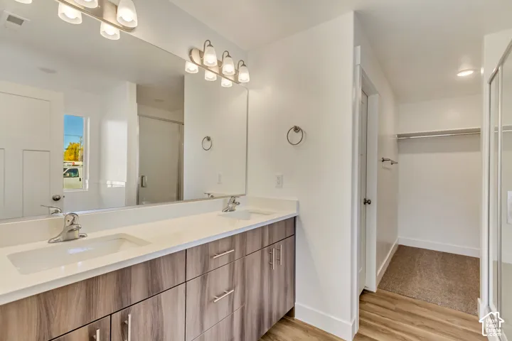 Double vanity with white countertops, wood-finish cabinetry, and chrome fixtures