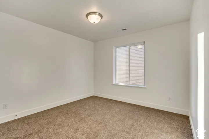 Neutral wall color, carpet flooring, window with blinds, and flush mount lighting