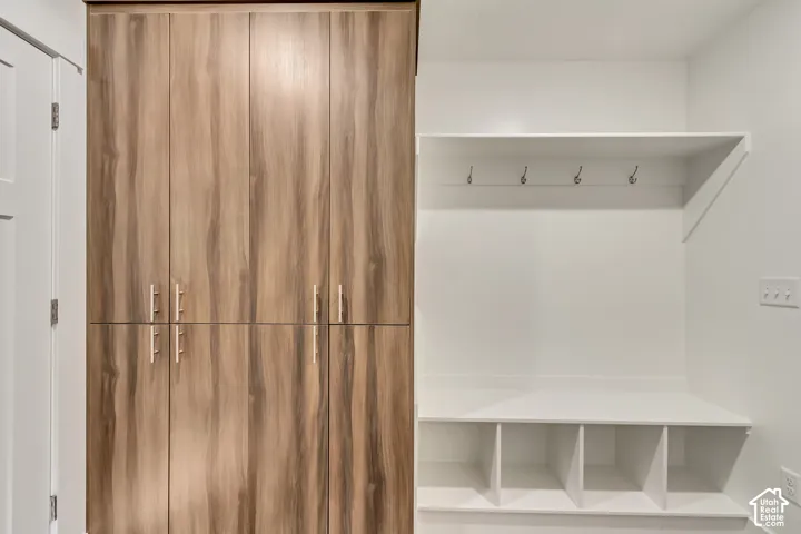 Wood-finish cabinetry with silver-tone hardware, built-in shelving, integrated storage cubbies, and wall-mounted hooks