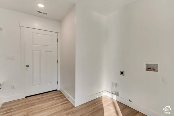 Wood-finish flooring, recessed lighting, and a paneled door with contemporary hardware