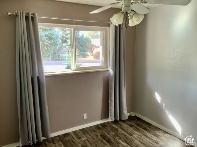 Window with white trim, wood-finish flooring, two-tone wall paint, and ceiling fan with light fixture