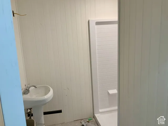 Pedestal sink with chrome fixtures and vertical paneling