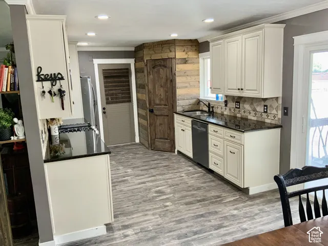 Recessed lighting, wood-finish flooring, white cabinetry, black countertops, and a patterned backsplash