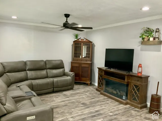 Recessed ceiling lighting, crown molding, wood-finish flooring, and a ceiling fan