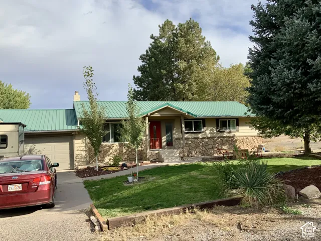 Single-story residence featuring a green metal roof, stone facade accents, and a red entry door