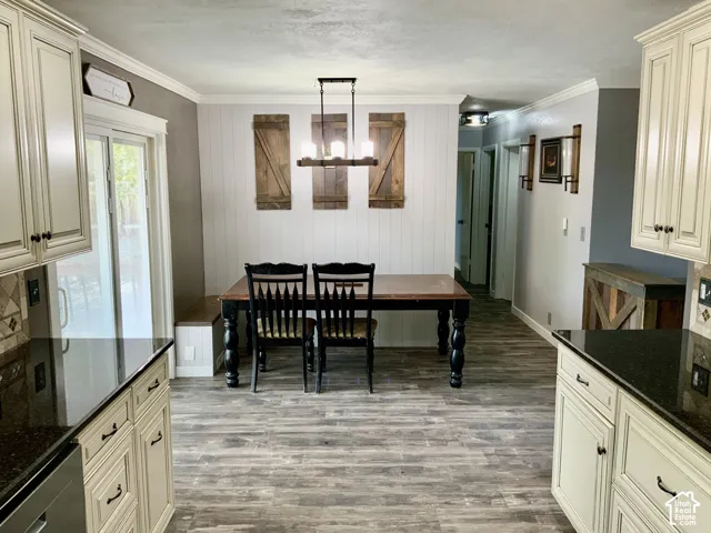 Kitchen and dining area featuring wood-finish flooring, cream cabinetry with dark hardware, dark countertops, and a sliding glass door