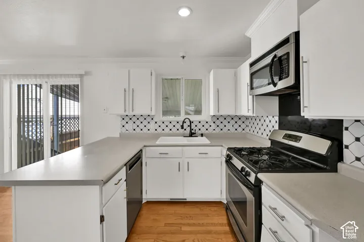 U-shaped kitchen featuring white cabinetry, gray countertops, a stainless steel range, a built-in microwave, and wood-finish flooring
