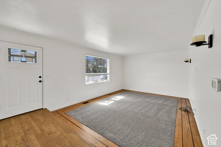 White paneled door with decorative glass inlay, wood-finish flooring, light gray carpeting, and wall-mounted sconces