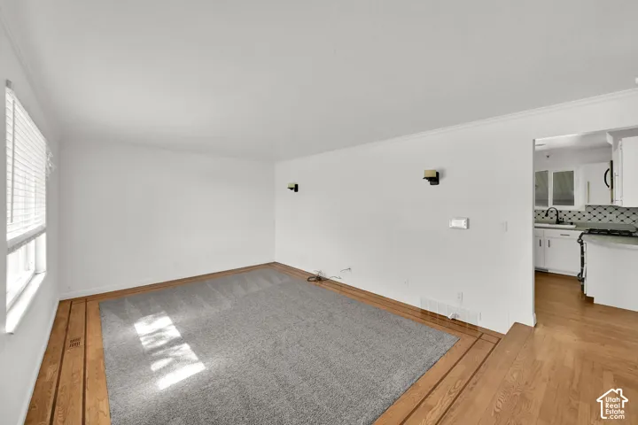 Hardwood flooring, wall-mounted sconces, and crown molding
