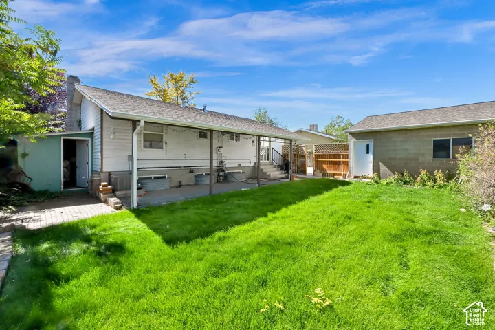 Expansive green lawn with a covered patio, exterior siding, and a detached structure