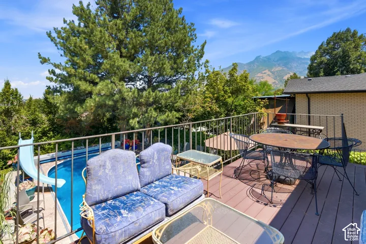 Expansive outdoor deck with composite decking and metal railing overlooking a swimming pool with a slide