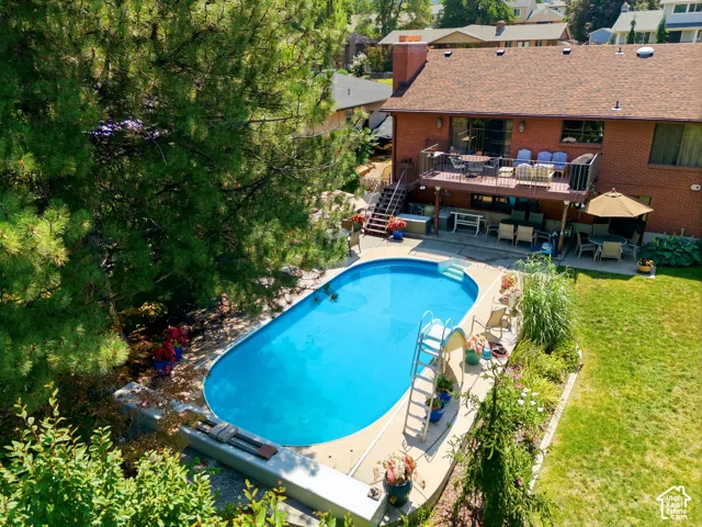 Brick exterior with a multi-level deck, featuring an inground swimming pool, concrete patio, and mature landscaping