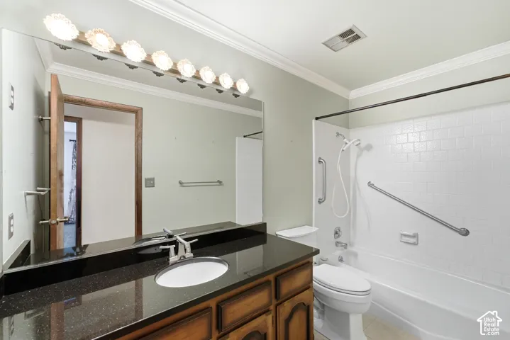 Bathroom featuring a wood-finish vanity with a dark speckled countertop, an integrated sink, and a combination shower and tub