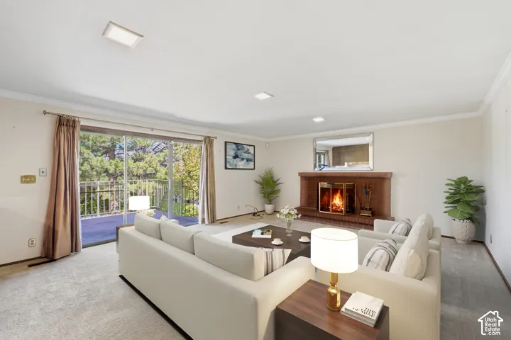 Spacious living area featuring a brick fireplace, sliding glass doors to outdoor deck, and recessed lighting