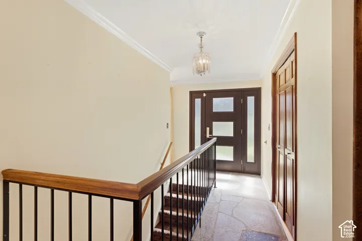 Entryway featuring a decorative pendant light, wood door with frosted glass panels, wood-finish bi-fold doors, and flagstone flooring