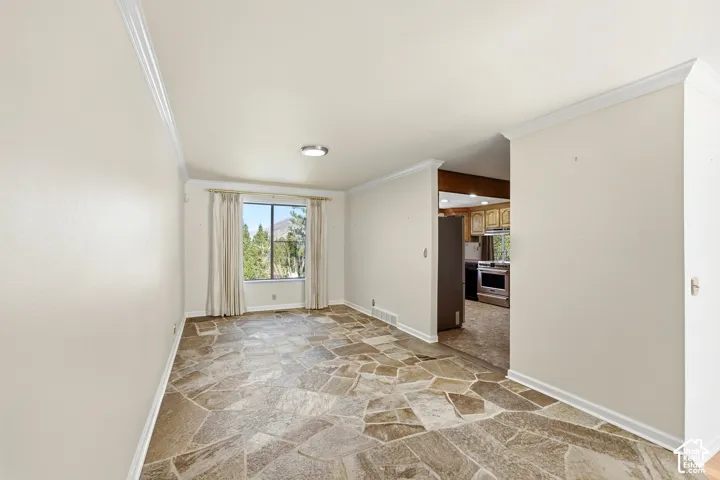 Irregular tile flooring, crown molding, and a window providing an outdoor landscape