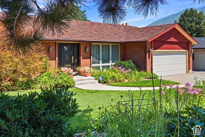 Brick exterior with red siding accents, attached garage, concrete driveway, and mature landscaping