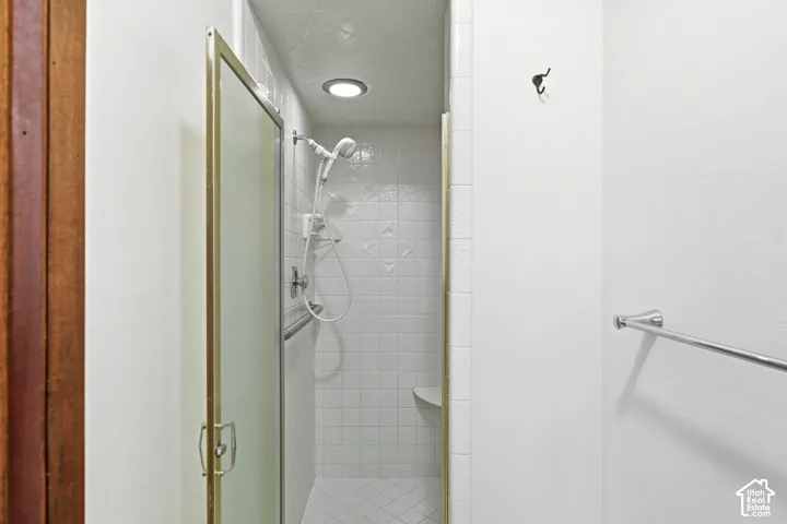 Tiled shower enclosure with a glass door, recessed lighting, and a built-in bench