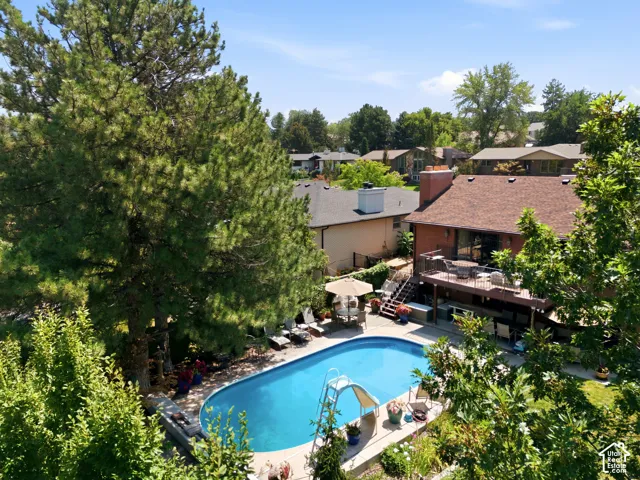 Outdoor swimming pool with integrated slide, multi-level deck, and surrounding concrete patio