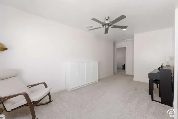 White walls with textured carpeting, featuring a ceiling fan with integrated lighting