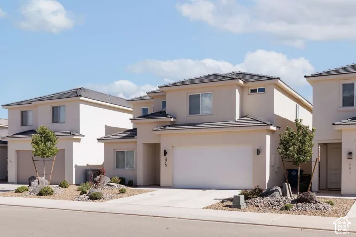 Stucco exterior featuring multiple windows and a two-car garage