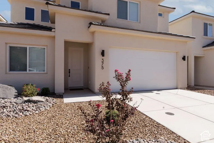Stucco exterior with a two-car garage, concrete driveway, and low-maintenance landscaping