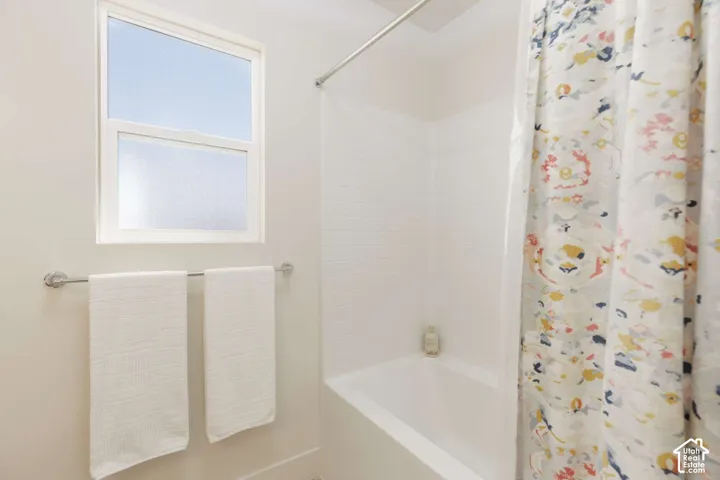Built-in bathtub with subway tile surround, chrome shower rod, and frosted window