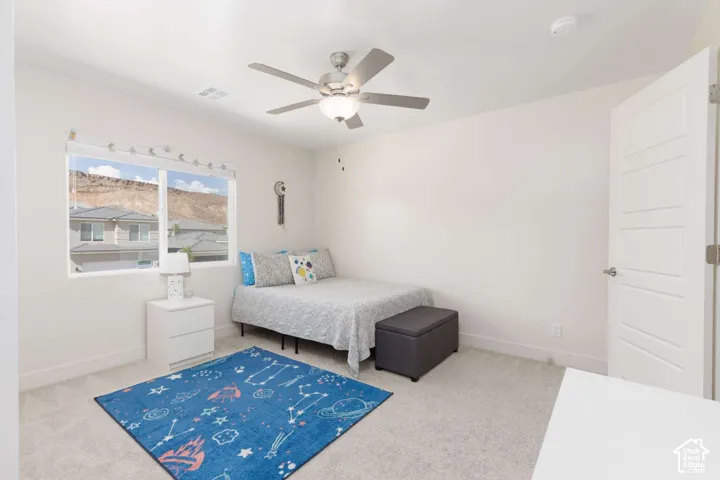White paneled door, light-toned wall-to-wall carpeting, window with mountain backdrop, and ceiling fan with integrated lighting