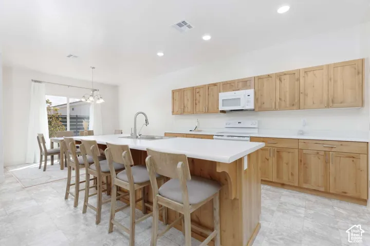 Kitchen featuring light wood cabinetry, white countertops, built-in microwave, and a large central island with an integrated sink