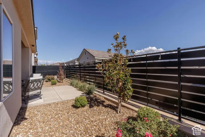Private patio with concrete pavers, gravel landscaping, and established plantings