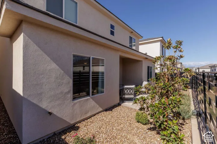 Covered patio with a concrete slab, stucco exterior, gravel landscaping, and a metal fence
