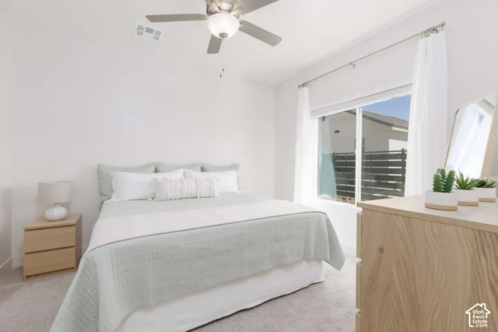 Recessed window with white trim, light-toned wood-finish dresser, ceiling fan with integrated lighting, and neutral carpeting