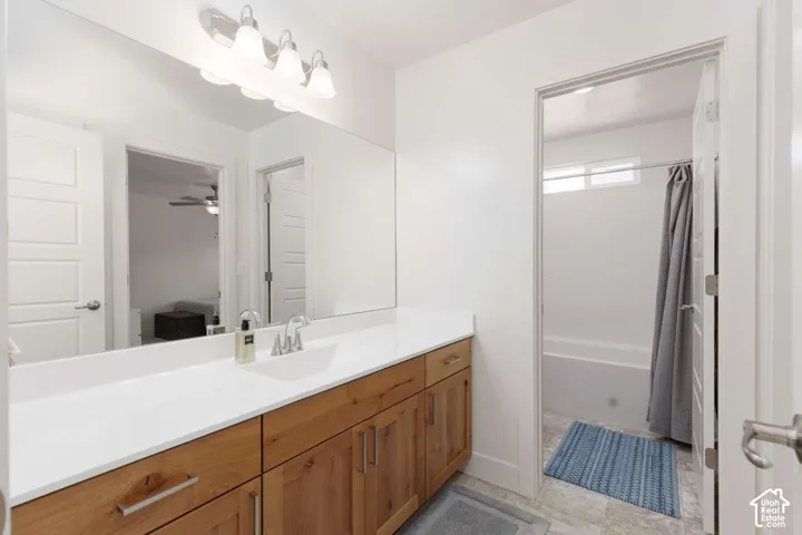 Wood-finish vanity with white countertop, chrome faucet, and expansive wall mirror