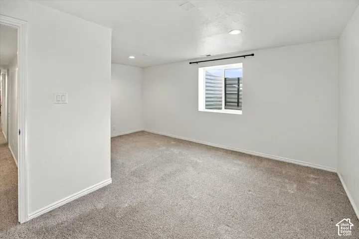 Recessed lighting illuminates neutral carpeting and white walls