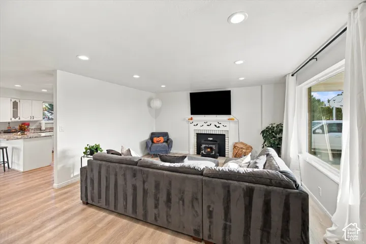 Recessed lighting, wood-finish flooring, white trim, white window framing, and a fireplace with a white mantel