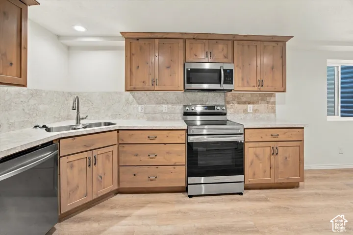Wood-finish cabinetry with stainless steel appliances, stone-finish countertops, and a tile backsplash