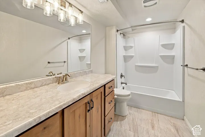 Wood-finish vanity with a single basin sink, large wall-mounted mirror, and a shower-tub combination
