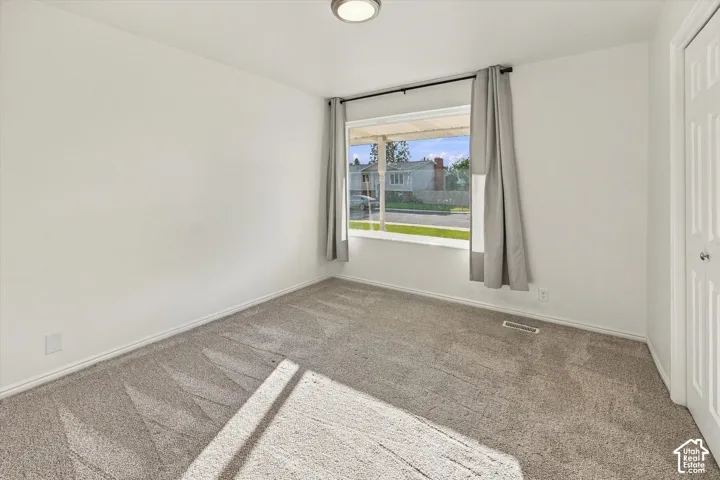 White painted walls, neutral carpet flooring, recessed ceiling light, and a white paneled door