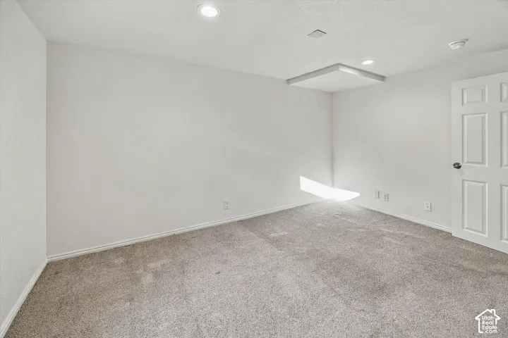 Recessed lighting, light-colored carpeting, white paneled door, and a drop ceiling detail