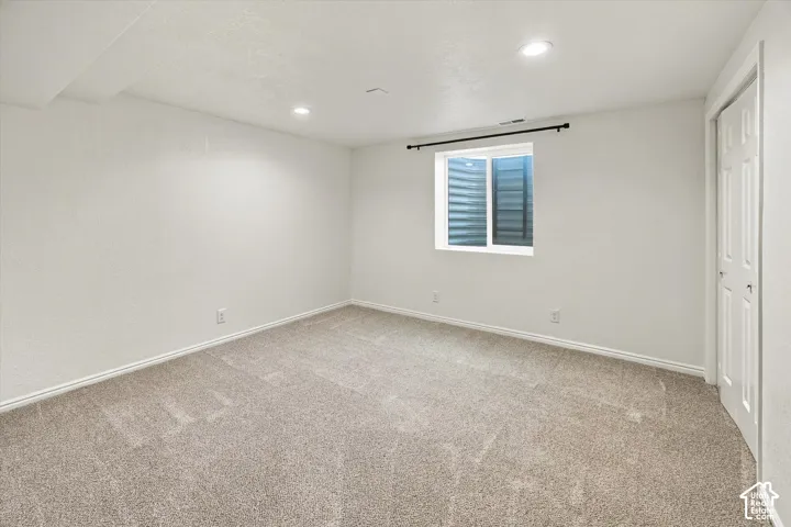 Recessed lighting illuminates the room, featuring a neutral carpet and white walls