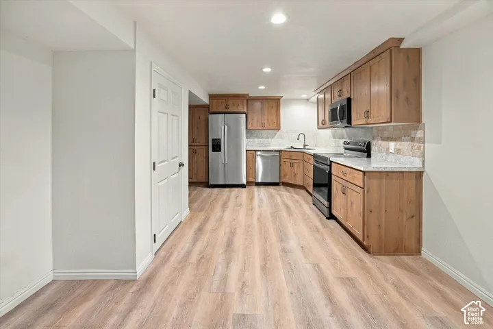 Kitchen featuring wood-finish flooring, recessed lighting, wood cabinetry, stone countertops, and stainless steel appliances