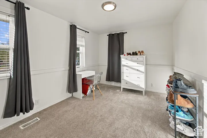 Wall-to-wall carpeting, two windows with blinds, a flush-mount ceiling light fixture, and wainscoting