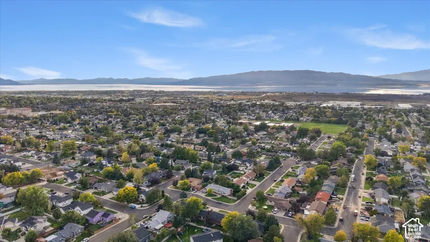 Expansive neighborhood featuring residential properties with mature trees, a central green space, and distant mountain and water features