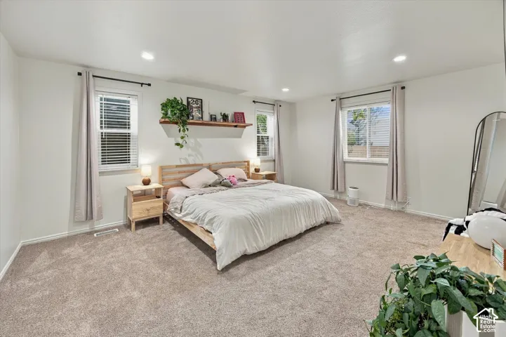 Carpeted flooring, multiple windows with blinds, recessed lighting, and a built-in wall shelf
