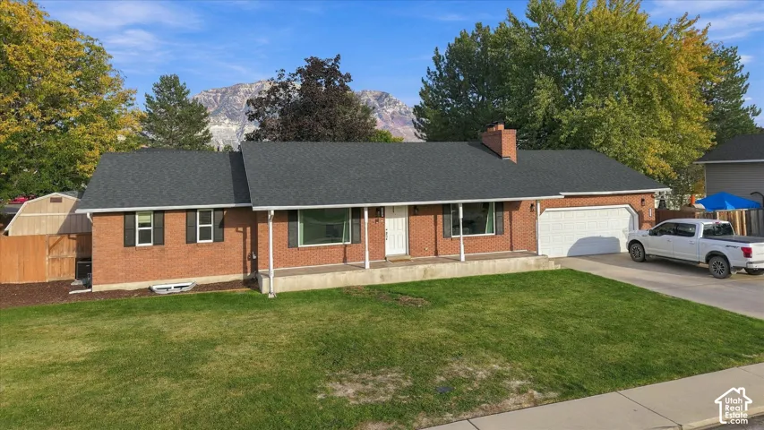 Brick exterior with a covered front porch, attached two-car garage, and a wood privacy fence